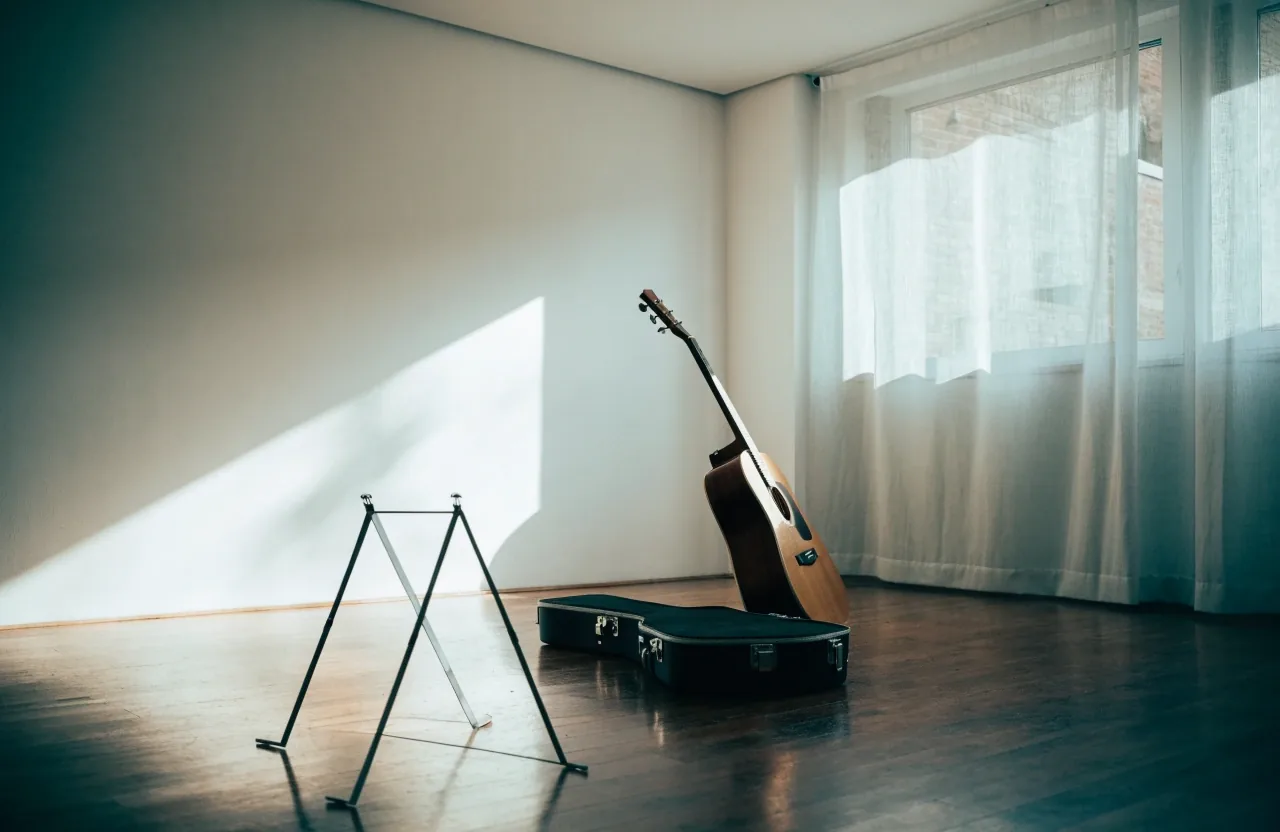 Acoustic guitar leaning against a wall in a bright teaching room with its case open nearby