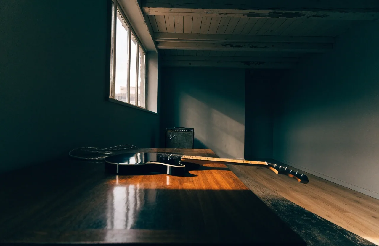 Electric guitar on a table with a small combo amplifier behind it in a practice room